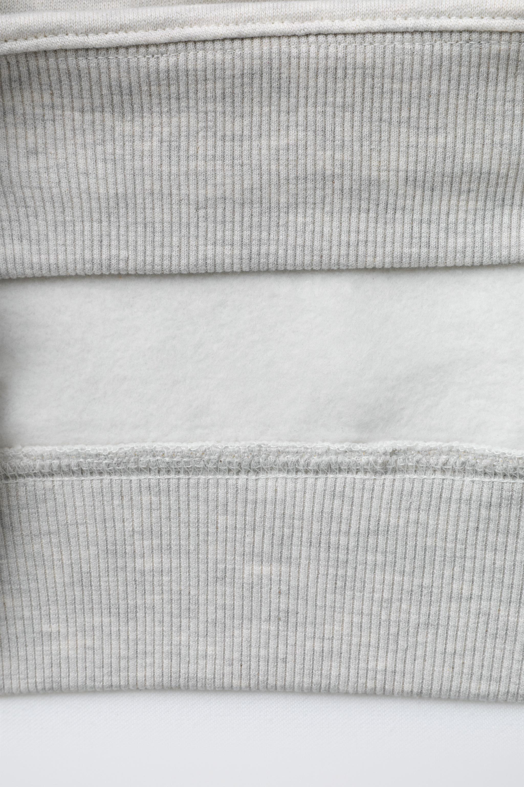 SWEAT À CAPUCHE AVEC INSCRIPTION BOUCLÉE